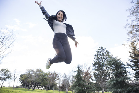 Porträt einer lächelnden jungen Frau, die in die Luft springt, lizenzfreies Stockfoto