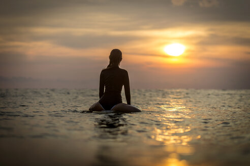 Indonesien, Bali, Surferin im Meer bei Sonnenuntergang - KNTF00636