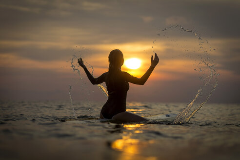 Indonesien, Bali, Surferin im Meer bei Sonnenuntergang - KNTF00637