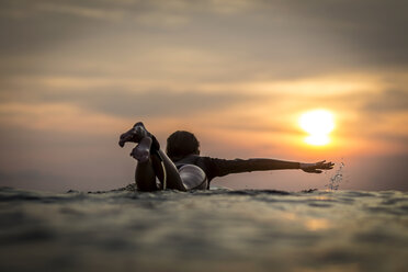 Indonesien, Bali, Surferin im Meer bei Sonnenuntergang - KNTF00639