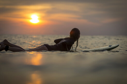 Indonesien, Bali, Surferin im Meer bei Sonnenuntergang - KNTF00640