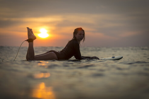 Indonesien, Bali, Surferin im Meer bei Sonnenuntergang - KNTF00641