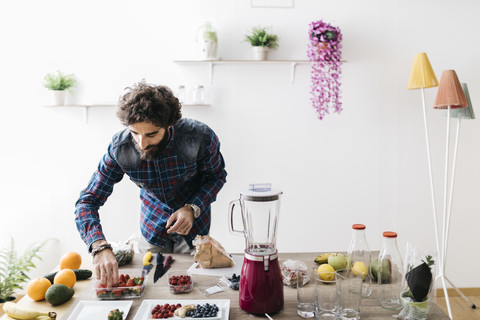 Mann, der zu Hause Smoothies mit frischem Obst und Gemüse zubereitet, lizenzfreies Stockfoto