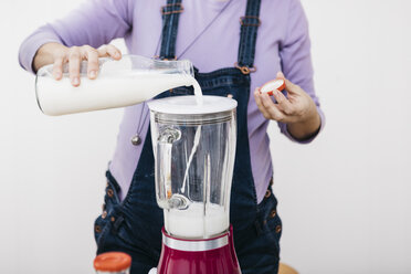Schwangere Frau gießt Milch in einen Mixer, um einen Smoothie zuzubereiten, Teilansicht - JRFF01208