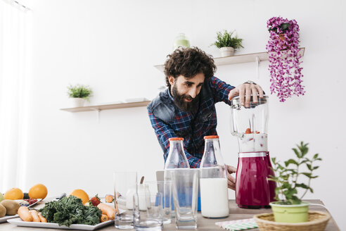 Man preparing smoothies with fresh fruits and vegetables at home - JRFF01216