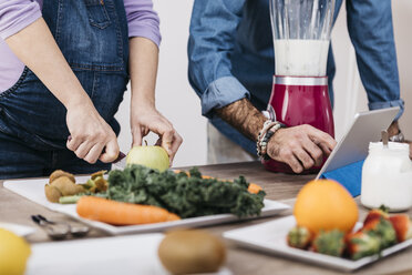 Hände eines Paares, das Früchte zubereitet und ein Tablet für die Zubereitung von Smoothies verwendet - JRFF01229