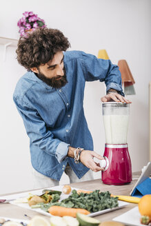 Man preparing smoothie with fresh fruits and vegetables at home - JRFF01233