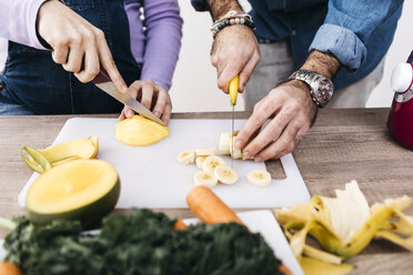 Hände eines Paares, das Früchte für die Zubereitung von Smoothies zerkleinert - JRFF01238