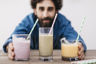 Mann zeigt drei Gläser mit verschiedenen Smoothies - JRFF01243