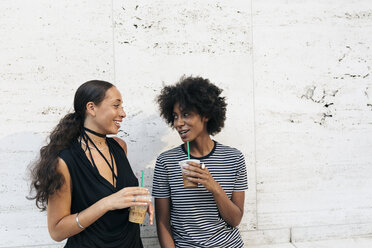 Two friends with drinks talking in front of a wall - GIOF01948