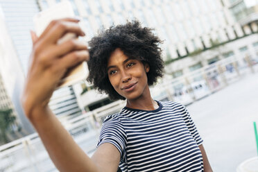 Porträt einer lächelnden jungen Frau, die ein Selfie mit ihrem Smartphone macht - GIOF01959