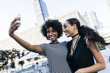 USA, New York City, zwei glückliche junge Frauen machen ein Selfie mit Smartphone - GIOF01960