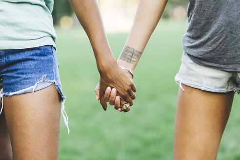Two women holding hands in a park - GIOF01975