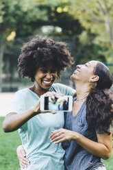 Zwei glückliche beste Freunde nehmen Selfie mit Smartphone in einem Park - GIOF01986