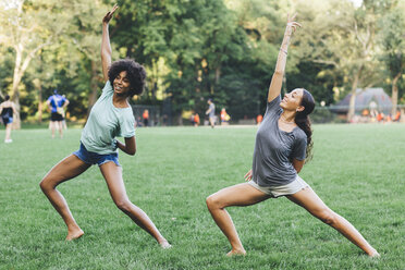 Zwei junge Frauen machen Yoga-Übungen in einem Park - GIOF01987