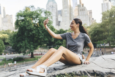 USA, Manhattan, lächelnde junge Frau macht Selfie mit Smartphone im Central Park - GIOF02000