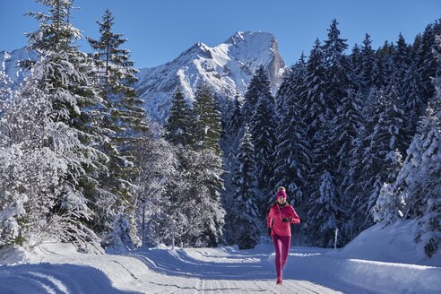 Österreich, Tirol, Karwendel, Rißtal, Frau joggt im Winterwald - MRF01700