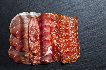 Slices of Spanish salami and Italian ham on slate - CSF27909