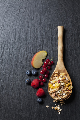 Wooden spoon of granola with dried fruits and various fresh fruits on slate stock photo