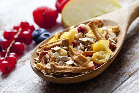 Wooden spoon of granola with dried fruits and various fresh fruits on wood stock photo