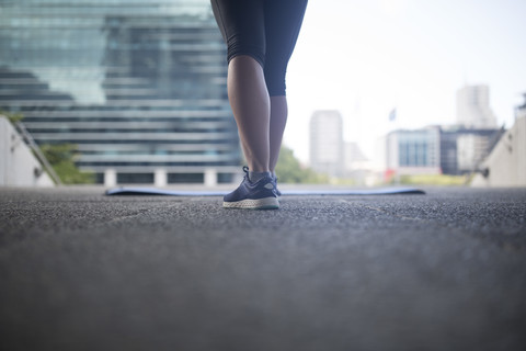 Beine einer Sportlerin neben einer Gymnastikmatte in der Stadt, lizenzfreies Stockfoto