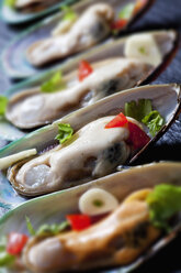 Green mussels with tomatoes, capsicum and garlic, on black slate slab - CSF27947