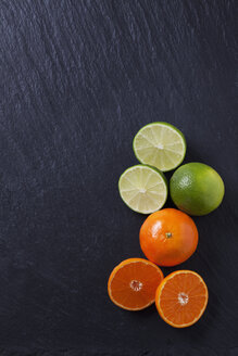 Limetten und Mandarinen auf schwarzer Schieferplatte - CSF27960
