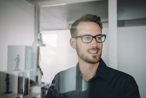 Smiling businessman behind glass pane - KNSF01034