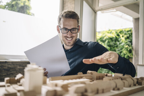 Smiling architect looking at urban development model - KNSF01036