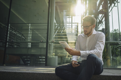 Businessman reading book in lobby - KNSF01071