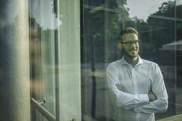 Smiling businessman looking out of window - KNSF01075