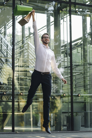 Excited man jumping with paper bags stock photo