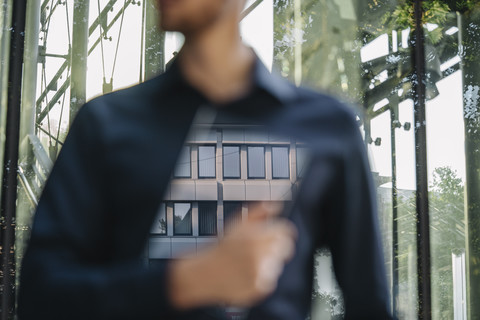 Geschäftsmann hält futuristisches tragbares Gerät mit Spiegelung eines Bürogebäudes, lizenzfreies Stockfoto