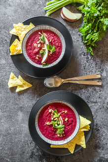 Zwei Schalen Rote-Bete-Suppe, garniert mit Apfelspalten, Erdnüssen und glatter Petersilie, serviert mit Tortilla-Chips - SARF03205