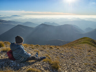 Italy, Marche, Boy watching Apennines at sunset - LOMF00516