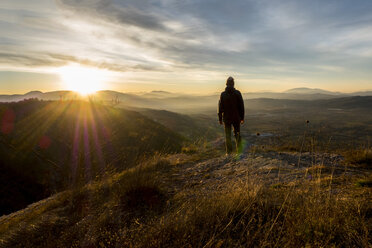 Italy, Umbria, Gubbio, Man watching sunrise on Sibillini mountain range - LOMF00518