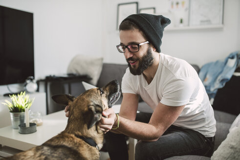 Young man at home tickling his dog - RAEF01745