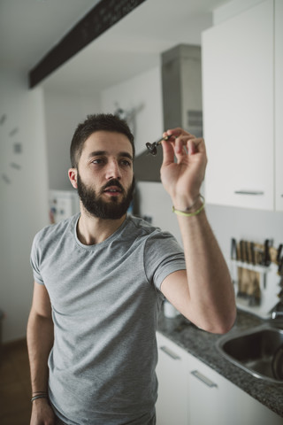Junger Mann spielt Darts in seiner Küche, lizenzfreies Stockfoto