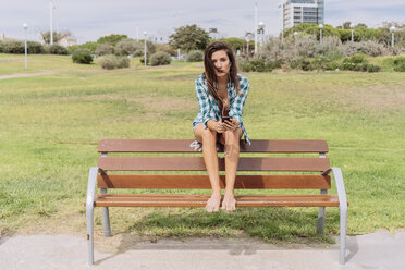 Junge Frau sitzt auf einer Bank am Strand - GIOF02029