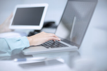 Geschäftsfrau mit Laptop, die ein digitales Tablet hält - ZEF12964