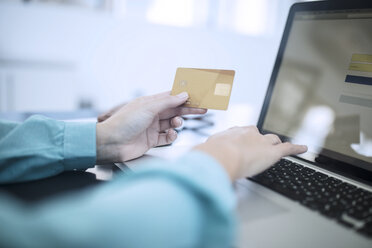 Frau hält Kreditkarte und tippt auf Computer, um eine Online-Zahlung zu tätigen - ZEF12981