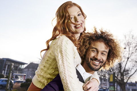 Happy young man carrying girlfriend piggyback stock photo