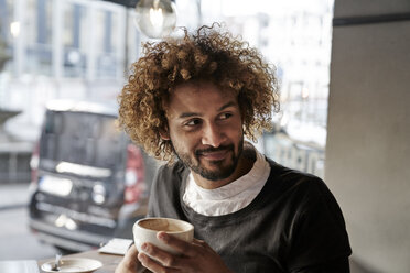 Smiling young man in a cafe - FMKF03496