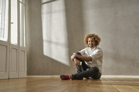 Lächelnder junger Mann in einem Zimmer sitzend, lizenzfreies Stockfoto