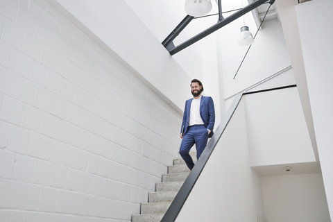 Lächelnder Geschäftsmann, der die Treppe hinuntergeht, lizenzfreies Stockfoto