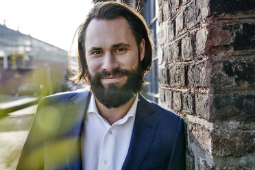 Portrait of smiling businessman outside brick building - FMKF03535