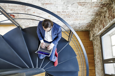 Geschäftsmann mit Laptop auf Wendeltreppe - FMKF03541