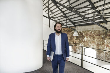 Businessman walking in office loft - FMKF03544