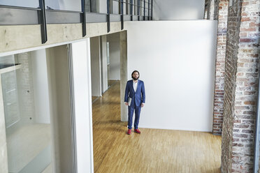 Portrait of businessman standing on empty office floor - FMKF03546
