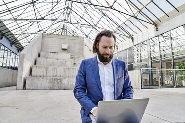 Geschäftsmann mit Laptop in einer Halle - FMKF03551